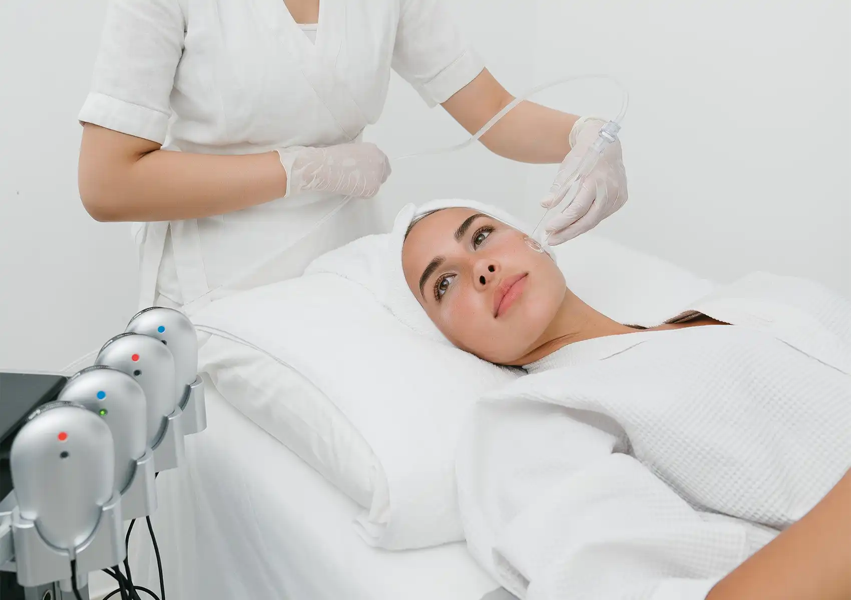 A female client relaxing on a treatment bed while a practitioner uses a specialized wand for a facial treatment at a beauty clinic bali.
