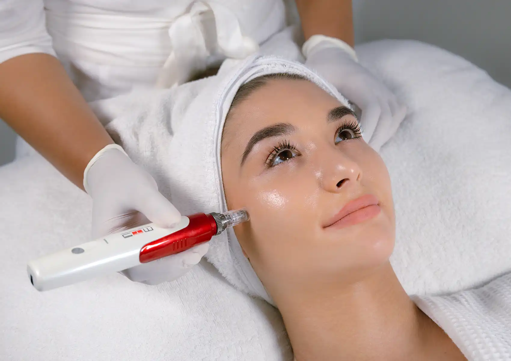 A woman looking upward while undergoing a cosmetic pen facial treatment administered by a skincare specialist at a beauty clinic bali.
