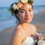 A radiant bride with glowing skin wearing a floral crown and holding a bouquet on the beach, showcasing the results of skincare treatments from a beauty clinic bali