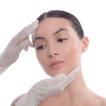 Gloved hands of a medical professional gently examining a woman's facial structure and skin condition during a consultation at a beauty clinic bali.