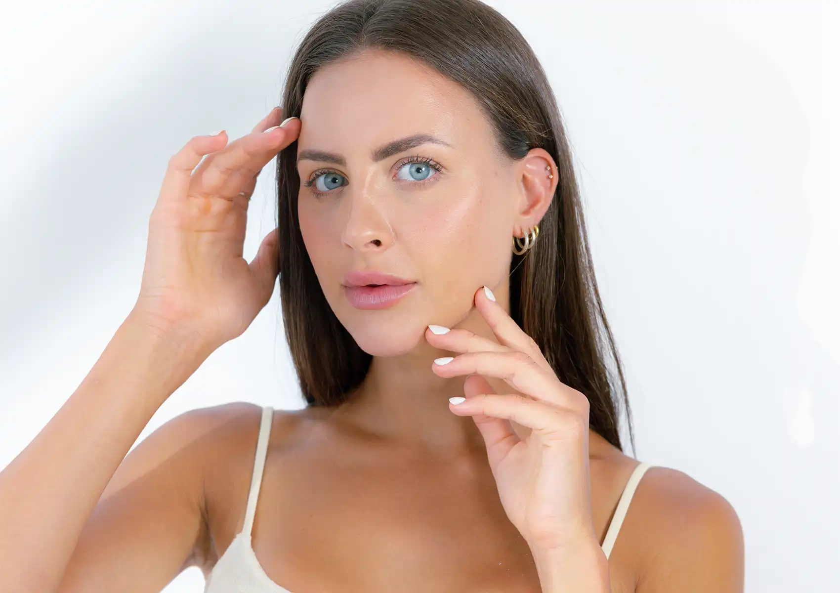 A woman with a glowing, clear complexion gently framing her face, demonstrating the results of advanced skincare treatments at a beauty clinic bali.