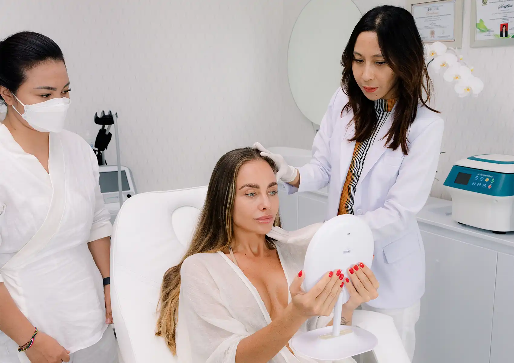A female patient holding a mirror while a professional examines her skin during a consultation at a beauty clinic bali